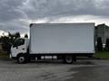 A 2018 Hino 195 box truck with a white cargo area and black chassis parked on a concrete surface