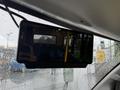 A rearview mirror of a 2020 Chevrolet Express showing a reflection of bus seats and a yellow pole inside a bus