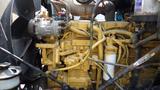 A close-up view of a large yellow engine with various metal components including pipes and wiring typical of a 2003 International 5600i truck engine