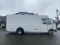A white 2012 Ford Econoline cargo van with a long body and a plain exterior parked at an industrial location