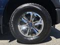A close-up of a chrome wheel from a 2015 Ford F-150 featuring multiple spokes and a prominent Ford emblem on the center cap