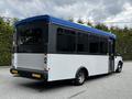 A 2019 Chevrolet Express bus with a blue roof and white body parked at an angle showcasing its rear and side windows