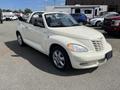 A 2005 Chrysler PT Cruiser convertible in cream color with a black interior and chrome wheels parked on a lot