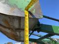 A measuring tape is positioned vertically against the bucket of a 2008 John Deere 3320 300X loader showing its dimensions