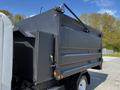 A 2016 Isuzu NPR truck with a black dump bed and a side-mounted tool box