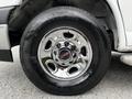 Close-up of a chrome wheel rim of a 2023 GMC Savana showing five circular spokes and a branded center cap with the GMC logo on a black tire