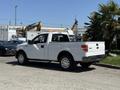 A white 2014 Ford F-150 pickup truck is parked with a visible bed and chrome wheels near a green area