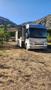 A 2007 Winnebago Adventure motorhome with a slide-out section extended and an awning deployed is parked on dry ground