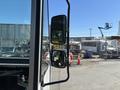 A 2019 Freightliner MT45 with side mirrors reflecting its environment and a view of the driver's cabin