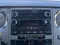 A dashboard of a 2016 Ford F-550 featuring a CD player radio system with buttons and a digital clock display