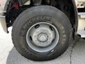 A close-up of a Michelin tire mounted on a 2010 Freightliner M2 106 truck showcasing a silver rim with multiple lug nut openings and a tread pattern designed for durability