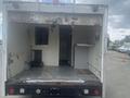 A 2004 Ford Econoline with an open rear door showing an empty cargo area equipped with metal flooring and small built-in storage compartments