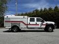 A 2009 Ford F-550 truck with a white body and red stripes featuring a utility bed designed for emergency services or maintenance work