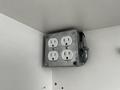 A metal electrical box with four white outlets mounted on a wall inside a climate controlled storage container