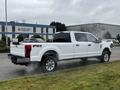 A 2020 Ford F-350 SD pickup truck in white with a crew cab and chrome wheels parked on a lot