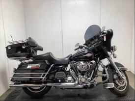 2009 Harley-Davidson FLHTC motorcycle with a black body chrome accents and a large windshield featuring saddlebags and a comfortable seat