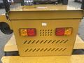 A yellow mini loader featuring rear lights with red and amber lenses and a compartment with a series of horizontal ventilation slits