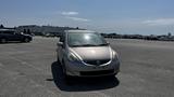 A silver 2006 Honda Fit parked on a flat surface with its windshield partially covered in dirt