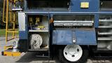 A blue 2009 International 4300 with open compartments showing metal storage bins and equipment layout including reels and tools