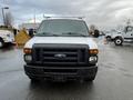 A white 2013 Ford Econoline van is parked facing forward with a black grille and bumper showing minor wear