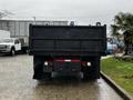 A black 2005 GMC C5 Duramax truck viewed from the rear displaying its flatbed and tailgate features