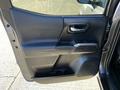 The interior door panel of a 2021 Toyota Tacoma featuring handle armrest and storage compartment with a sleek design