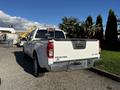 White 2015 Nissan Frontier pickup truck with a silver bumper and SV 4x4 badge on the tailgate seen from the rear