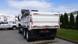 A 2014 International 7500 truck with a white dump bed and dual rear wheels parked with its rear facing the viewer