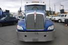 A blue 2015 Kenworth T660 truck with a chrome grille and orange lights on top facing forward