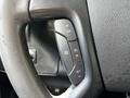 The steering wheel of a 2013 Chevrolet Express showing control buttons for cruise control including plus and minus signs and an indicator light