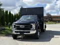 A black 2017 Ford F-550 with a large enclosed trailer attached is parked with its front facing the viewer