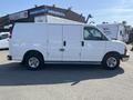 A white 2016 GMC Savana van with sliding side doors and black wheels is parked, showcasing its side profile