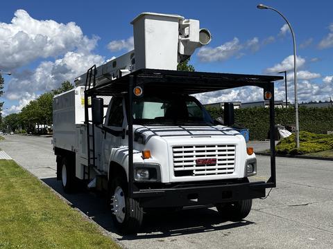 A white 2006 GMC C7C00 truck with a mounted equipment platform and spotlight on the roof parked on the side of the street
