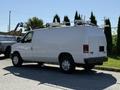 A white 2011 Ford Econoline van with a roof rack is parked with its side facing the viewer