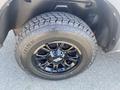 A close-up of a black tire and wheel from a 2021 RAM 1500 featuring a rugged tread pattern and a glossy black rim design