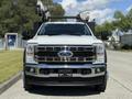 A white 2023 Ford F-550 with a chrome grille and a sturdy front bumper is positioned facing forward, showcasing its robust design and powerful build