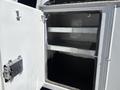 An open compartment of a 2016 Ford F-550 featuring two metal shelves on the interior