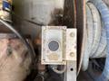 A metal control panel with a circular button in the center surrounded by wires and machinery components