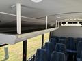 Interior view of a 2020 Chevrolet Express showing overhead luggage rack and seating area with blue patterned upholstery
