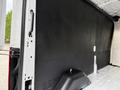 Interior view of a 2022 Ford Transit van showing a black wall panel and the vehicle's floor with a storage compartment visible
