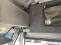 Interior view of a 2012 Ford Econoline showing the vehicle's metal framework and insulation with a round green and white label displayed in the upper corner