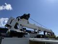 A white 2023 Ford F-550 equipped with a crane apparatus mounted on the bed for lifting and heavy-duty tasks