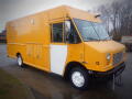 A yellow 2008 Freightliner MT45 chassis with a boxy design featuring a large front windshield and multiple side compartments for storage