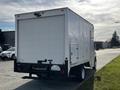 A 2013 Ford Econoline cargo van with a white rear and no visible markings parked on a street