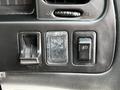 A close-up view of the control panel of a 2003 Mitsubishi Delica featuring several buttons and switches in a textured finish