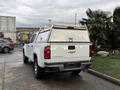 A white 2019 Chevrolet Colorado with a truck cap and ladder rack visible from the rear showing the Chevrolet logo and Colorado lettering