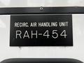 A black rectangular sign displaying the text RECIRC AIR HANDLING UNIT RAH-454 in white letters