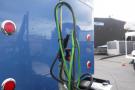 A 2015 Kenworth T660 with a blue exterior features green and black hoses connected to the rear along with red and white reflectors