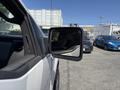 A 2014 Ford F-150 side mirror reflecting a view of nearby cars in a parking lot