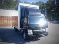 A 2013 Mitsubishi Fuso FE 160 truck with a black front and white box trailer